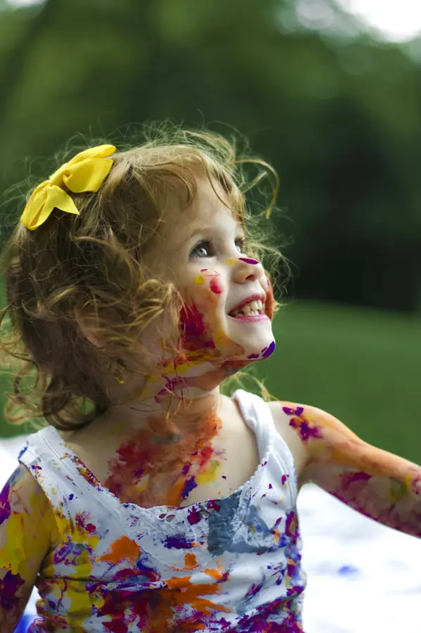 Niña sonriendo con las manos pintadas de colores